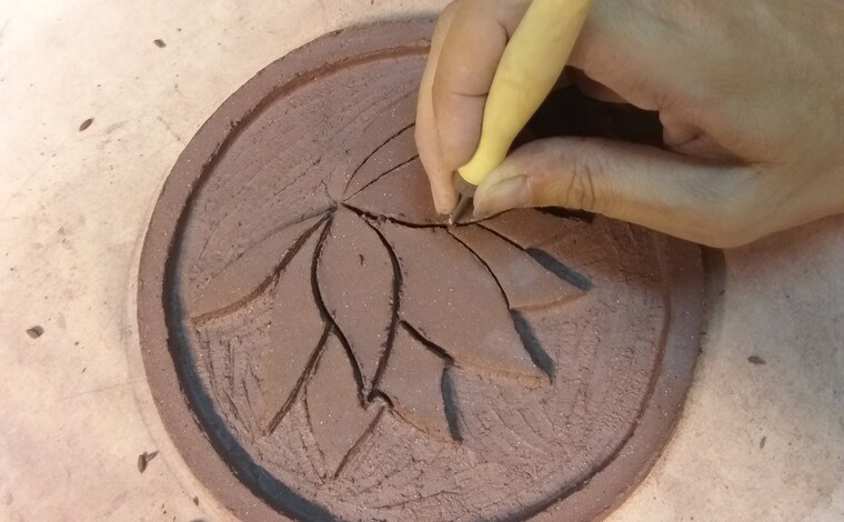 Grabado a mano de una flor de loto sobre una placa de barro