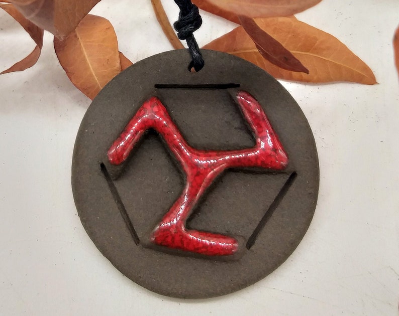 Colgante de cerámica marrón con un símbolo rojo