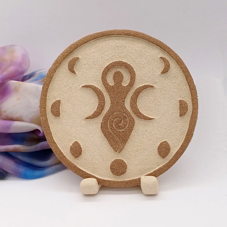 Plato de cerámica con figura femenina y tres fases lunares en relieve