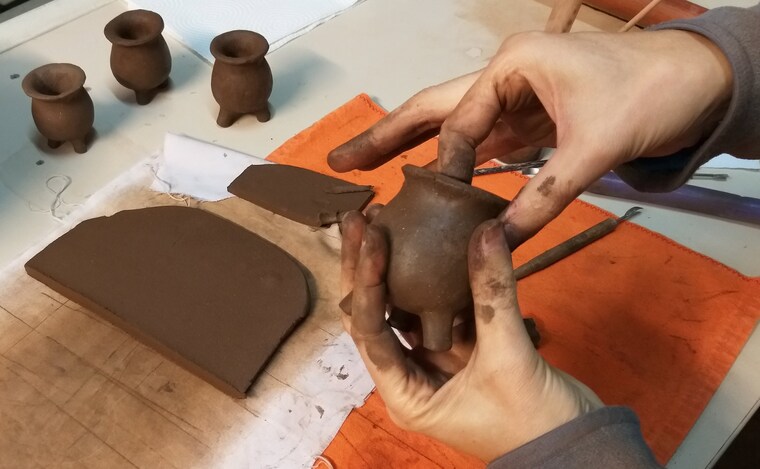 Una pieza de cerámica recién modelada junto a otras piezas en proceso
